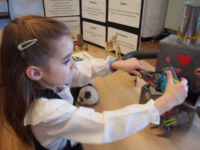 Charlotte demonstrates her toy cleaning robot invention